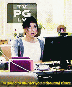 a woman sitting in front of a computer with a tv pg lv sign above her