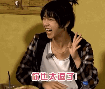 a young man is sitting at a table with a bottle of water in front of him and laughing .