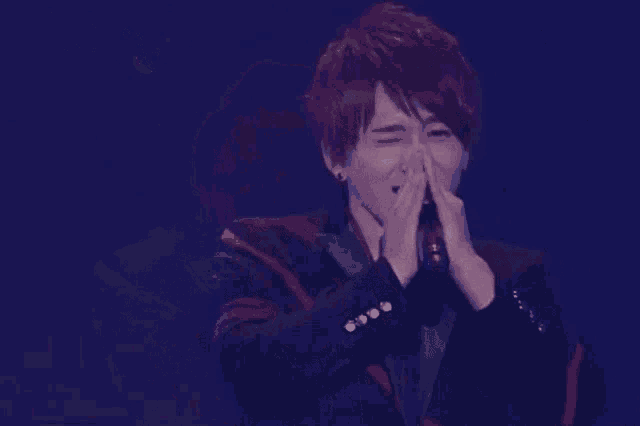 a young man is singing into a microphone on stage .