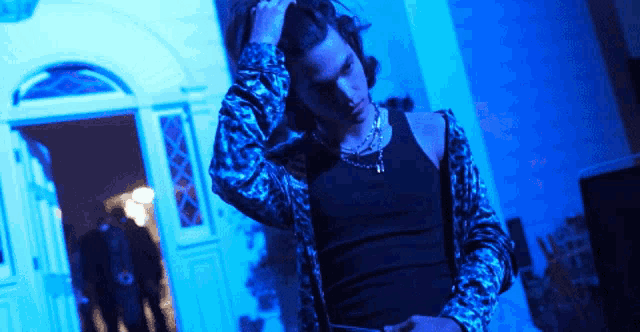 a man in a black tank top is standing in front of a blue doorway