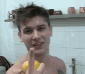 a man without a shirt is holding a lemon in his hand and giving the middle finger