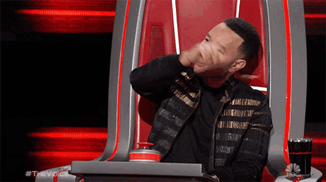 a man sitting in a chair with the word the voice on the bottom right