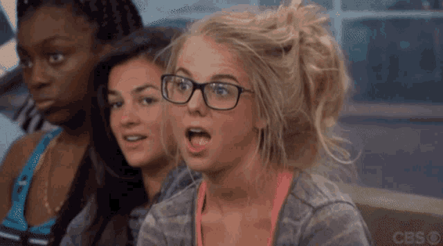 three women are sitting on a couch with one wearing glasses and a cbs logo in the corner