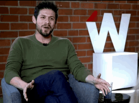 a man is sitting in front of a large white letter w