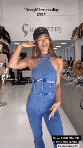 a woman in a denim jumpsuit is standing in front of a store that says hairqueen