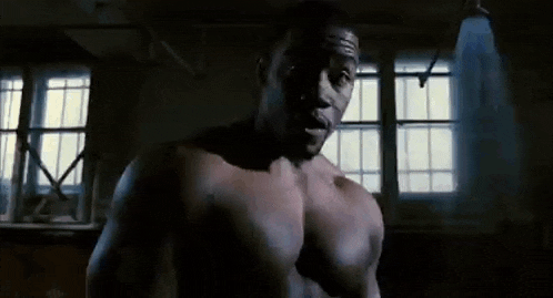 a shirtless man is standing in a dark room with a window in the background .