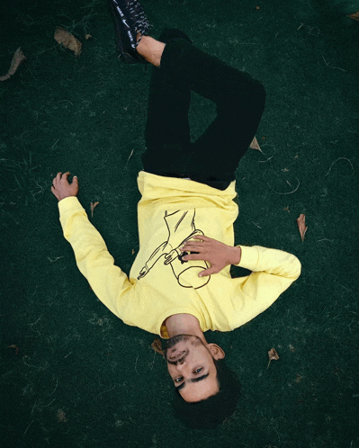 a man in a yellow shirt is laying on his back on the ground