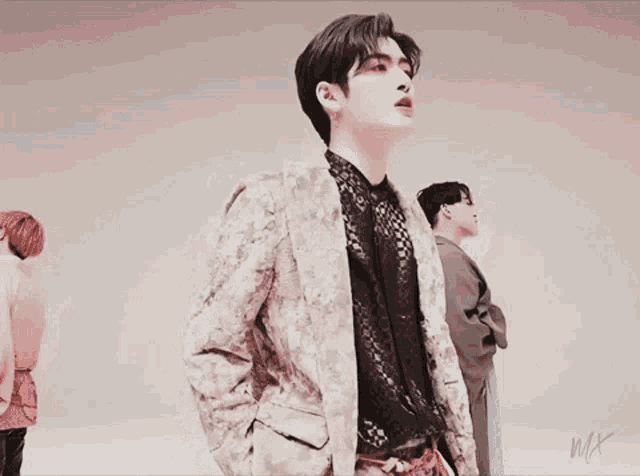 a group of young men are standing next to each other and one of them is wearing a floral jacket .