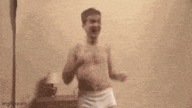 a shirtless young man in white underwear is dancing in a room .