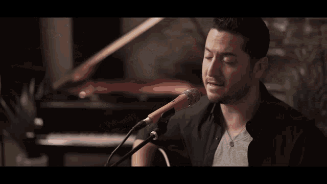a man is singing into a microphone while playing an acoustic guitar