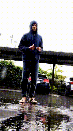 a man in a hooded jacket stands in a puddle of water