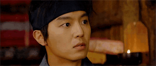 a young man wearing a headband is looking at the camera .