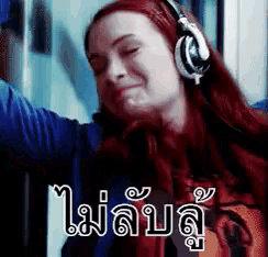 a woman with red hair is wearing headphones and making a funny face .