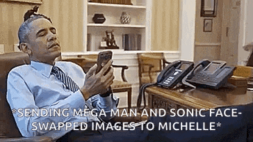 barack obama is sitting at a desk looking at his phone .