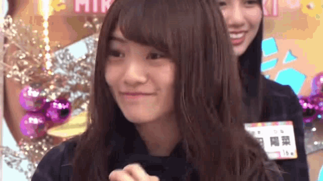 a girl with long hair is smiling and making a funny face .