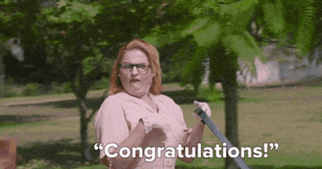 a woman is holding a broom and saying congratulations