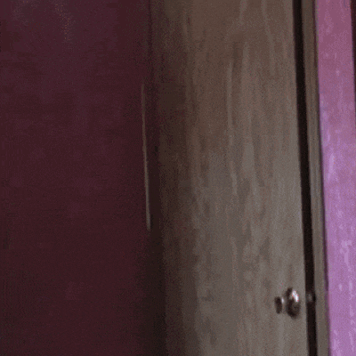 a woman in a blue shirt is walking out of a door