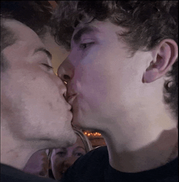 two men kissing in front of a crowd of people