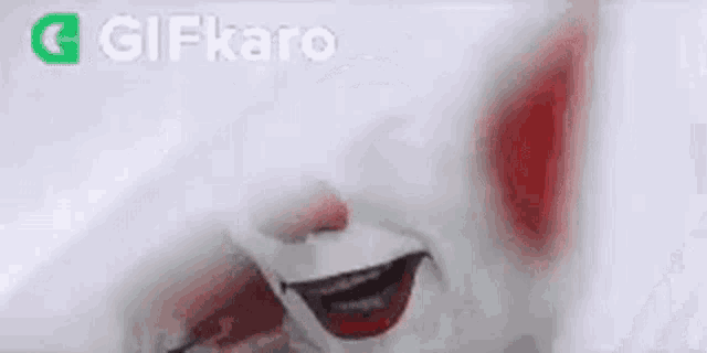 a close up of a clown 's face with a red nose .