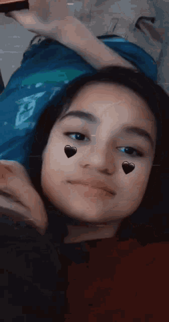 a girl with hearts on her face is laying on the floor .