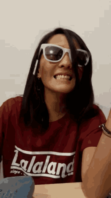 a woman wearing sunglasses and a lalaland shirt
