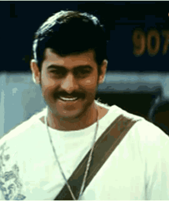a man with a mustache is wearing a white shirt and a brown necklace .
