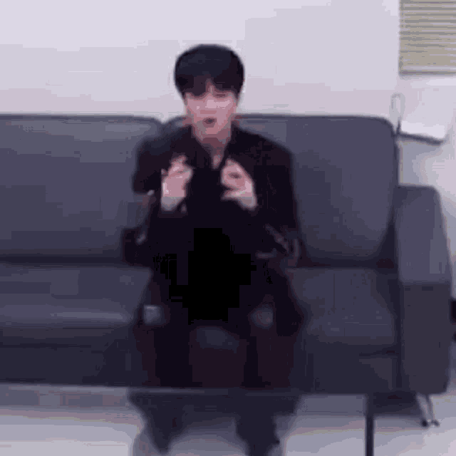 a man is sitting on a couch in a room holding a remote control .