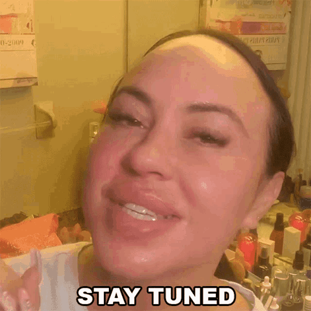 a woman says " stay tuned " in front of a mirror