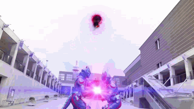 two robots are fighting each other in front of a building with a purple light coming out of it .