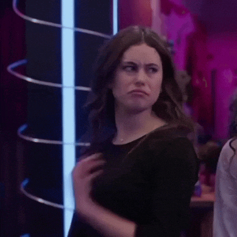 a woman in a black dress is making a funny face while standing in a room .