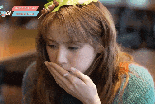a woman wearing a headband with a skewer on it is covering her mouth with her hands