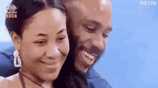a man and a woman are smiling at each other and hugging each other .