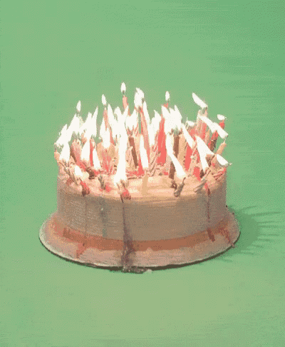 a birthday cake with many lit candles and the words feliz aniversario on the bottom