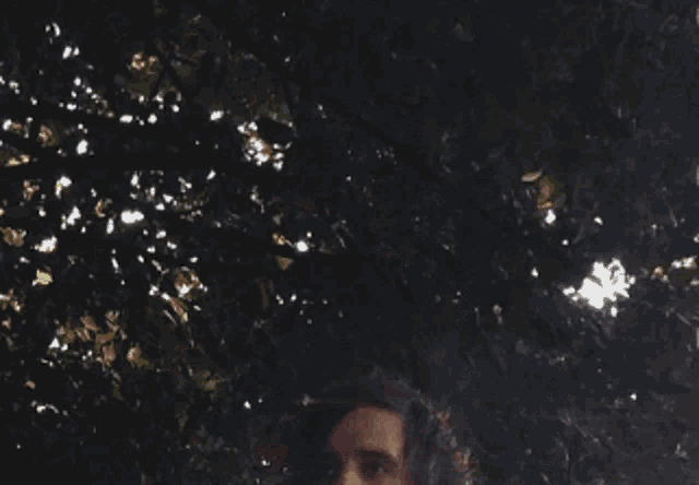 a young man with his eyes closed is standing in front of a tree