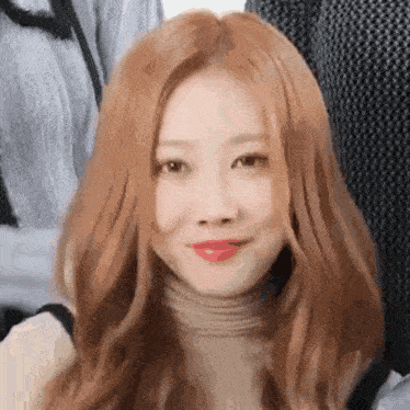 a close up of a woman with long red hair and red lipstick .