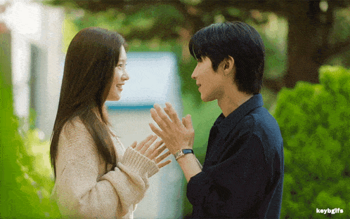a man and a woman are touching each other 's hands with a keybgifs watermark in the corner