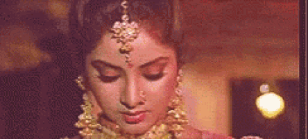 a close up of a woman 's face with her eyes closed wearing a headpiece and earrings .