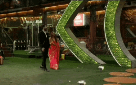 a man and a woman are standing in front of a large green arrow .