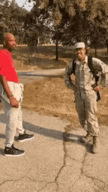 a man in a red shirt is talking to a soldier in a military uniform .