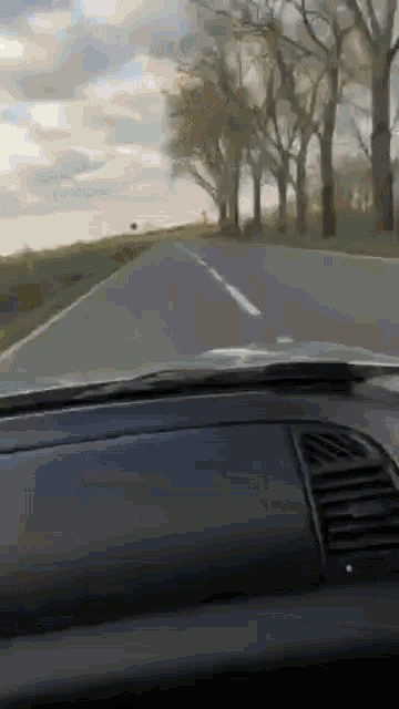 a car is driving down a road with trees on both sides .