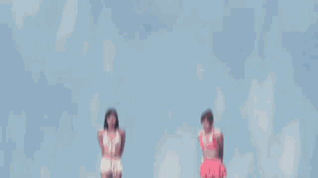two women in bikinis are standing in the air