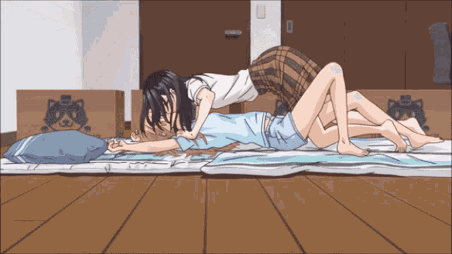 a couple of anime girls are laying on a blanket with boxes in the background