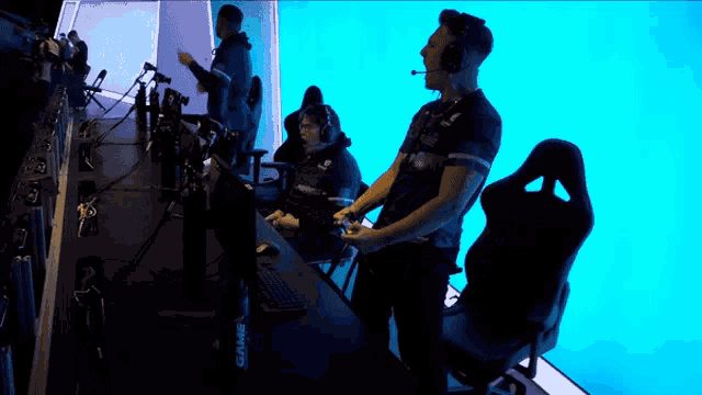 a man wearing a headset holds a remote control in front of a screen that says game on it