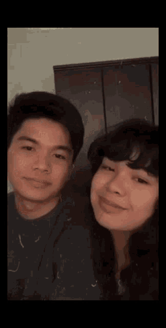 a man and a woman are posing for a picture together and smiling at the camera .