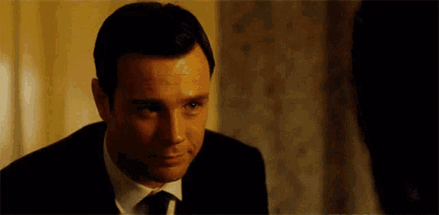 a man in a suit and tie is smiling while looking at another man .