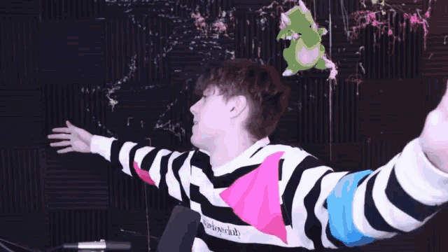 a man with his arms outstretched in front of a wall with a drawing of a dinosaur