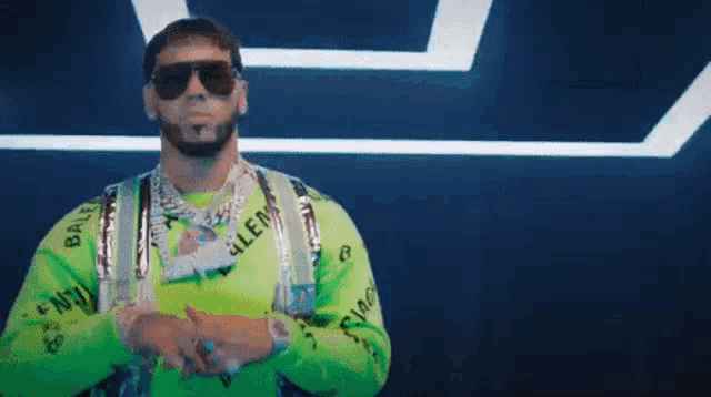 a man wearing sunglasses and a neon green sweater is standing in front of a dark background .
