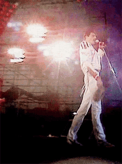 a man is singing into a microphone while walking on a stage