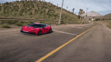 a red sports car is driving down a road with mountains in the background