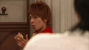a young man in a red shirt and tie is holding a yellow object in his hand .